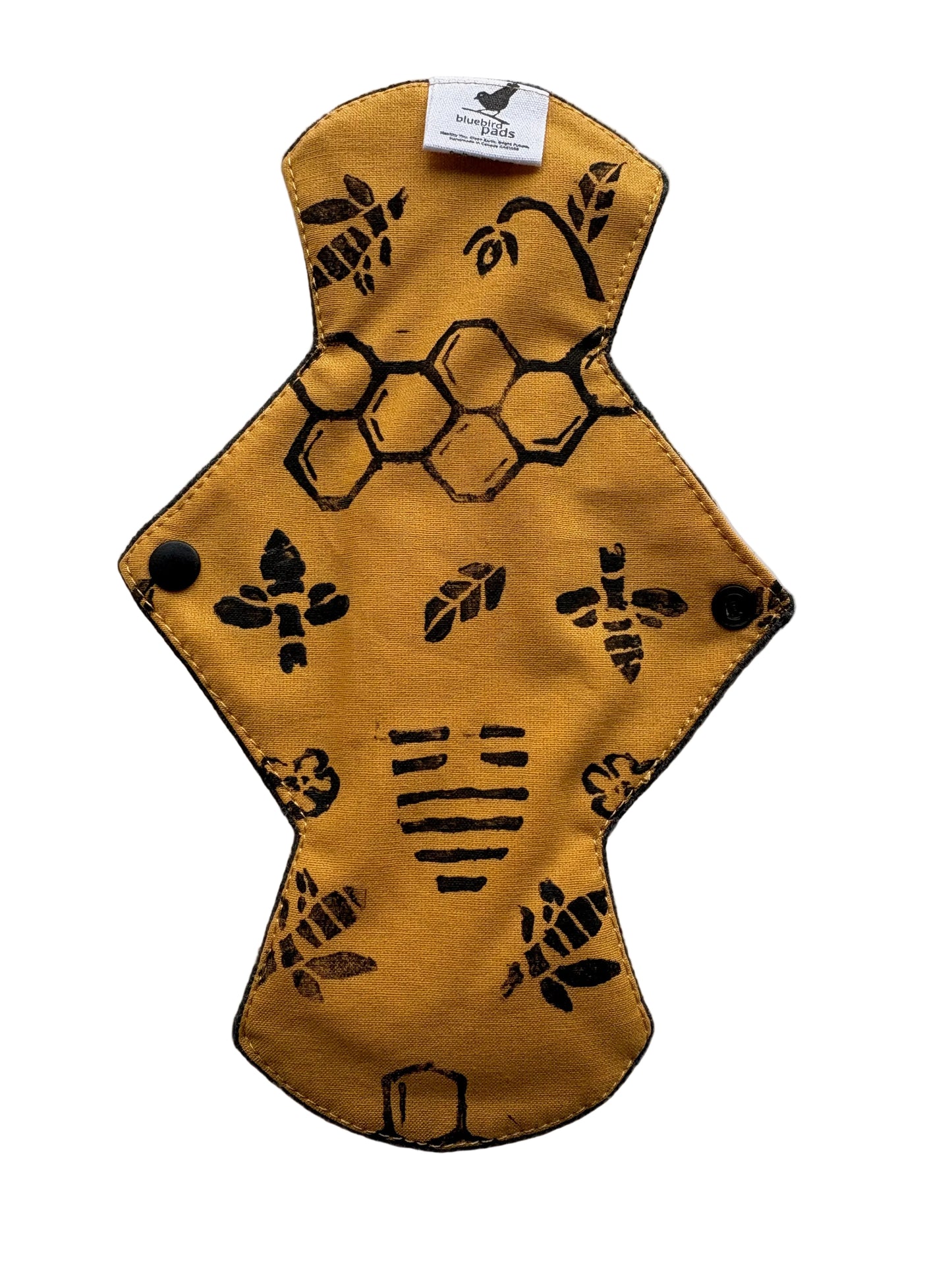 Mustard coloured cloth pad with black honeycomb and bee pattern